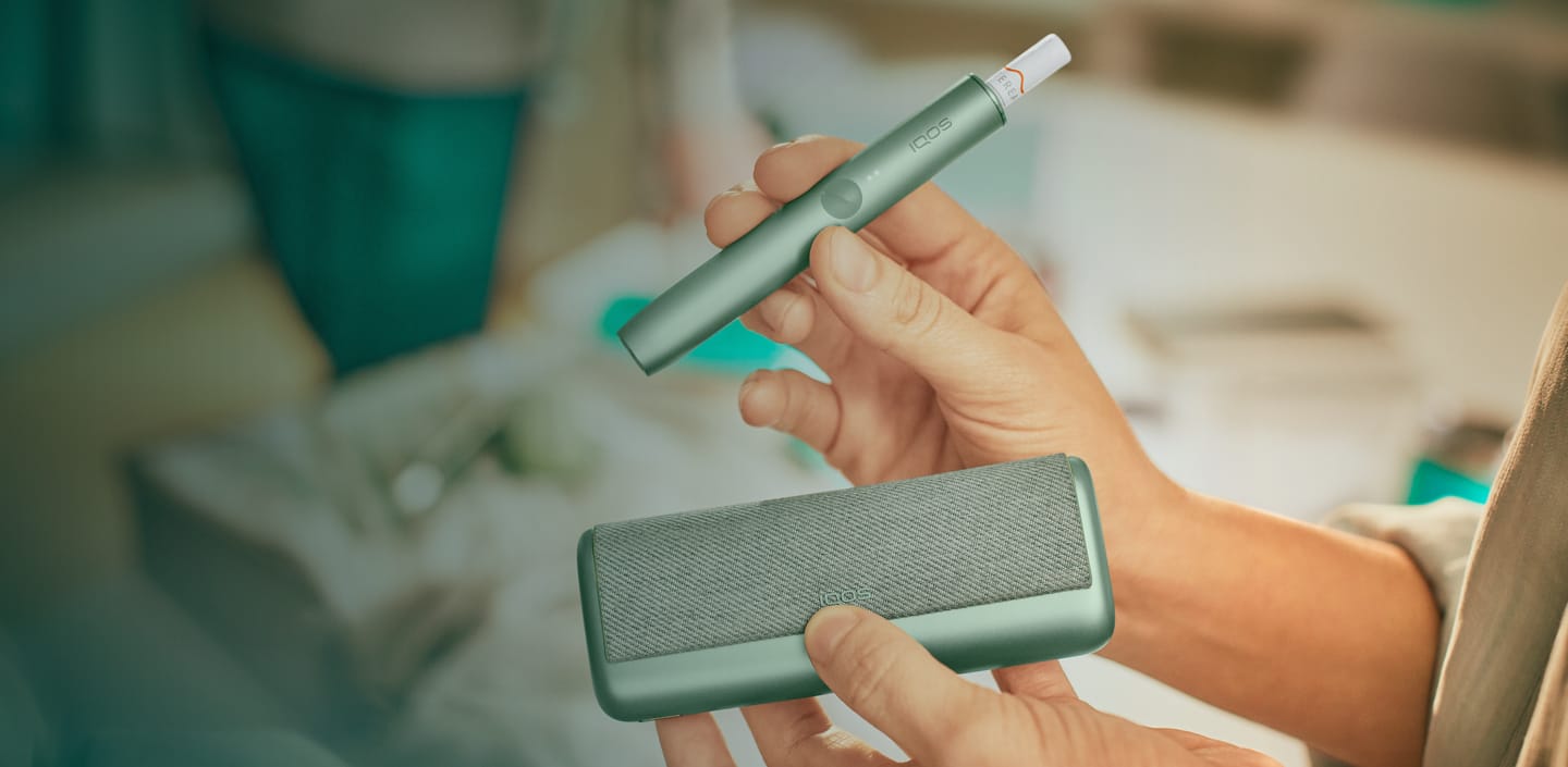 جهاز IQOS ILUMA PRIME باللون الأخضر الزمرّدي وشاحن الجيب.